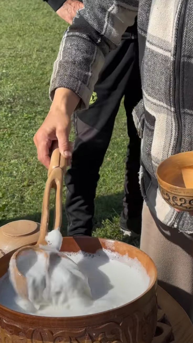 Seorang lelaki sedang mengaduk minuman berwarna putih dengan peralatan berbahan kayu