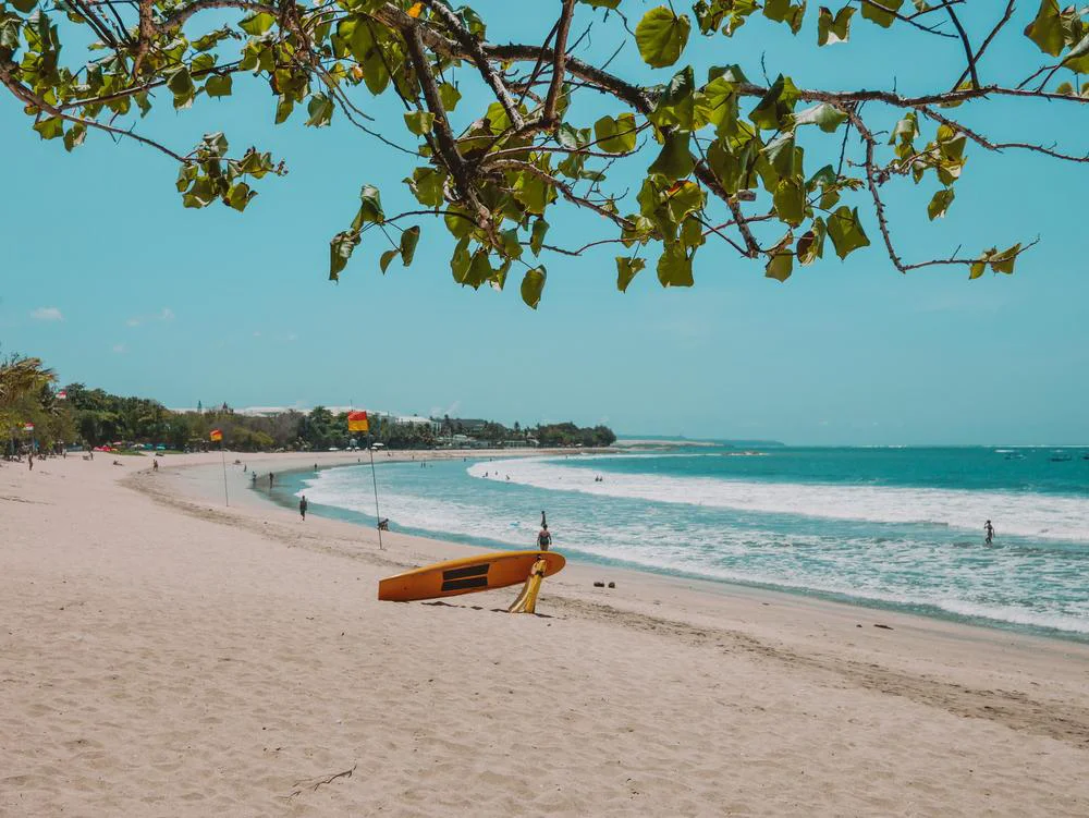 Hamparan pasir putih yang luas di sepanjang garis Pantai Kuta di Bali pada siang hari.